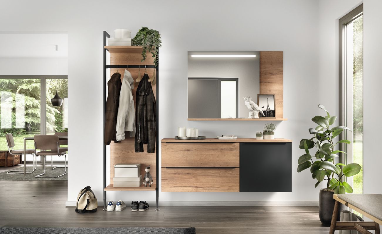 Moderne Garderobe mit Holzregal, Spiegel und Schubladen. An der Wand hängen Jacken, daneben steht eine Pflanze.